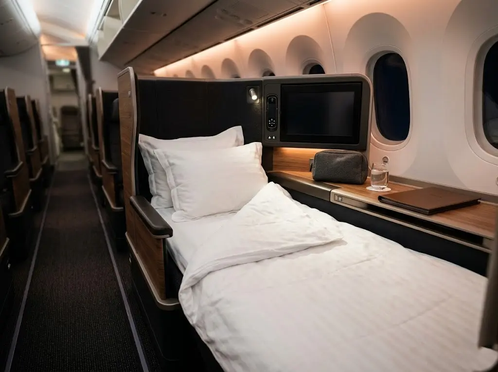 Business class airplane flatbed seat with warm cabin mood lighting and amenity kit