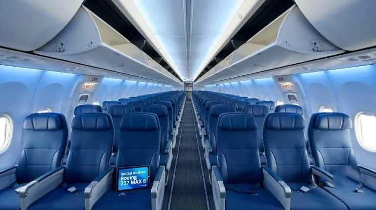 Empty cabin of a United Airlines Boeing 737 MAX 8 showing the blue seats and large overhead bins in the Sky Interior.